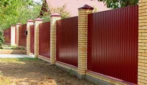 Вид деревянного забора с кирпичными фундаментом и стойками